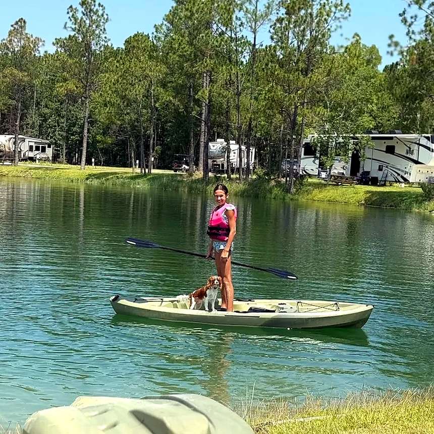 Child and dog paddling on the lake with RV sites along the far bank at Lake LaCroix