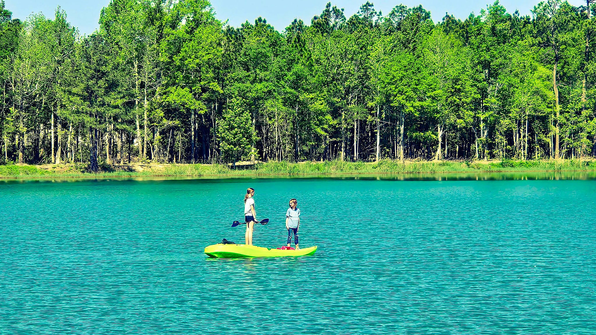 Kids kayaking on the calm lake at Lake LaCroix RV Resort in Bay St. Louis