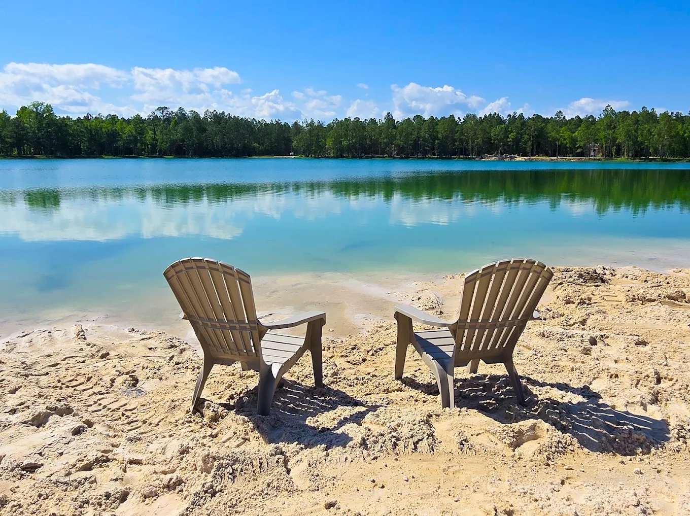 Adirondack chairs on the sandy beach beside the turquoise lake at Lake LaCroix