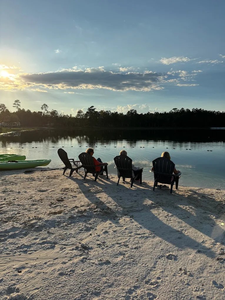 Guests relaxing by the lake at dusk at Lake LaCroix RV Resort