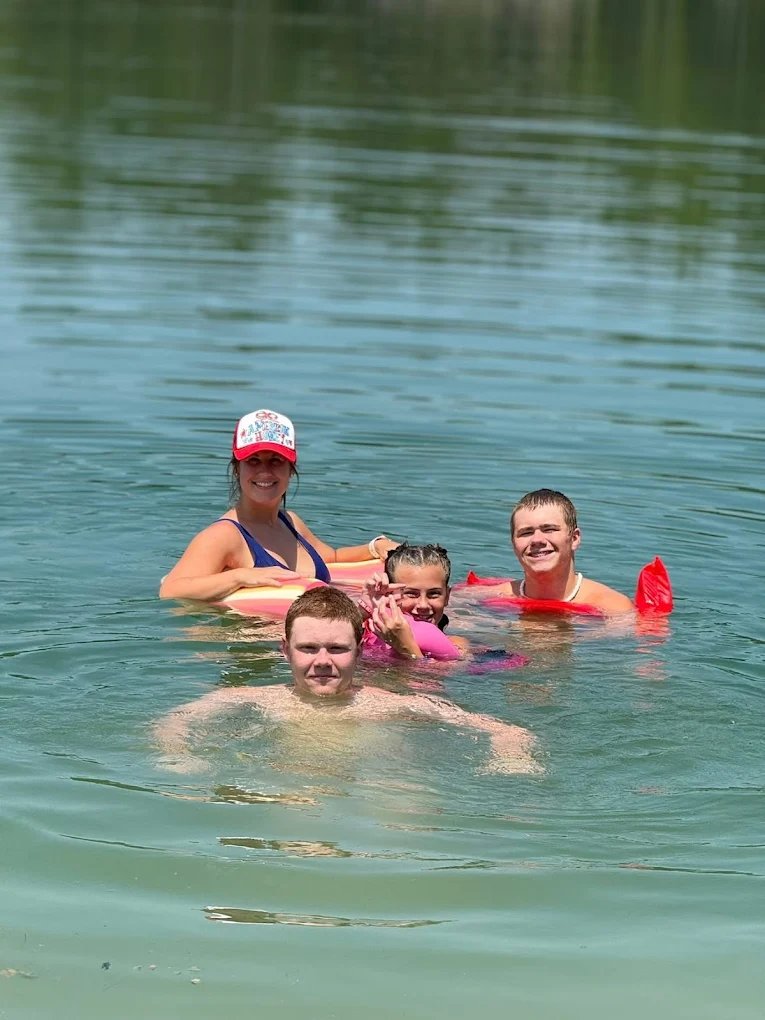 Family swimming together in the clear lake at Lake LaCroix RV Resort