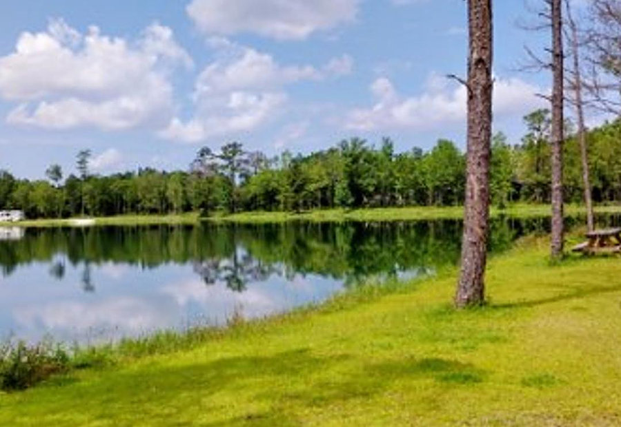 RV parked at a wooded lakeside site with a mirror-calm lake at Lake LaCroix