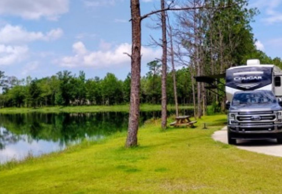 Fifth-wheel RV and truck at a lakefront concrete site at Lake LaCroix RV Resort