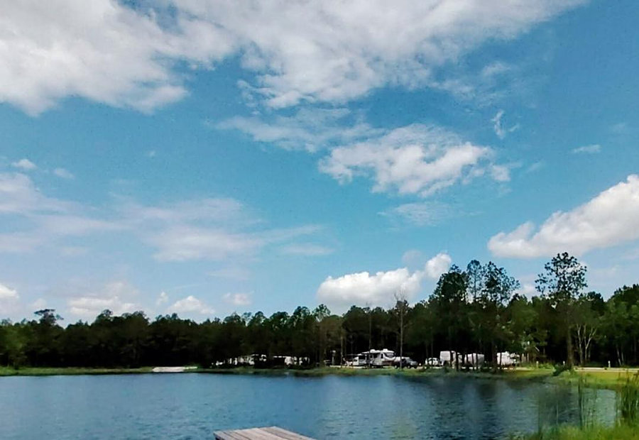 Calm lake and dock under a big Gulf Coast sky at Lake LaCroix RV Resort